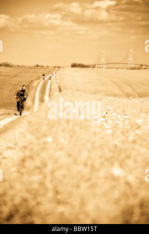 El Largo Viaje con bujías. Los ciclistas de cercanías tomar un camino de tierra a través de un campo de amapolas desde el puente Great Belt Foto de stock