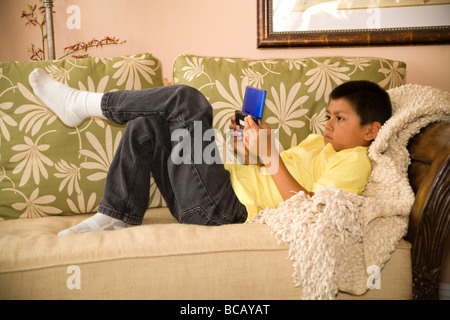 Niño hispano jugando Nintendo Gameboy DS MR Foto de stock