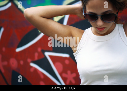 Mujer joven con gafas de sol, las manos detrás de la cabeza Foto de stock