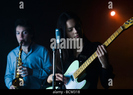 Los jóvenes músicos tocando la guitarra eléctrica y el saxofón en el night club