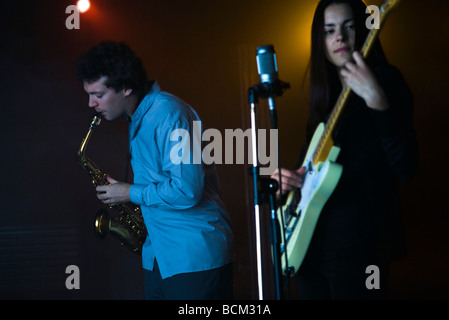 Los jóvenes músicos tocando el saxofón y guitarra eléctrica en night club