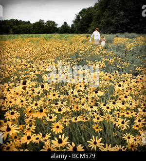 Madre e hija caminando por un campo de flores amarillas