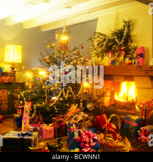 Regalos bajo el árbol de navidad con luces de bengala y la chimenea. Foto de stock