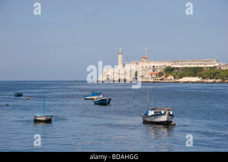 Pequeños barcos de pesca dot la entrada del puerto en la parte frontal del faro viejo y la ciudadela, al final del Malecón, La Habana Vieja Foto de stock