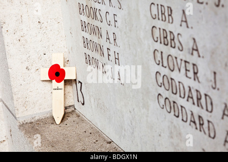 Lone poppy cruzar a la izquierda en una pared con nombres de soldados desaparecidos en el Menin Gate WW1 memorial en Ypres, Bélgica, Europa Foto de stock