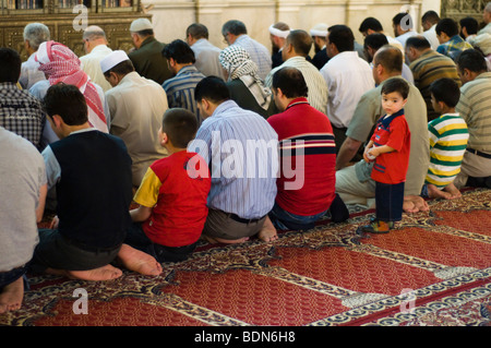 Los hombres y los niños orar en la mezquita de los Omeyas (Gran Mezquita de Damasco). Foto de stock