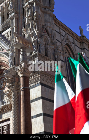 El seccionado campanario de mármol del Duomo (catedral) y la bandera italiana de la Piazza del Duomo, Siena, Toscana, Italia. Foto de stock