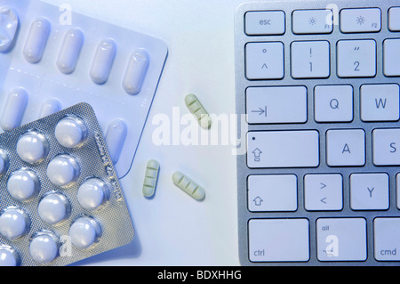 Los empeines y psicofármacos junto al teclado de un ordenador, la imagen simbólica para el dopaje en el trabajo Foto de stock