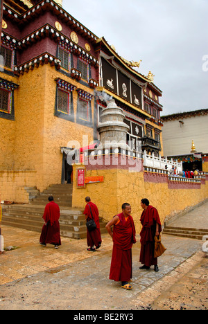 Monjes budistas tibetanos en hábitos rojos en frente del templo, el monasterio de Ganden Sumtseling Gompa, Zhongdian, Shangri-La, Yunnan Pr Foto de stock