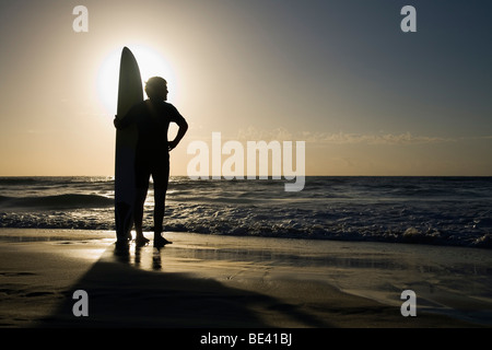 Hombre de pie con tablas de surf al amanecer. Bondi Beach. Sydney, New South Wales, Australia