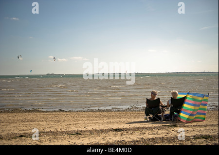 Playa con una pareja de ancianos viendo kite surf en el mar. Foto de stock