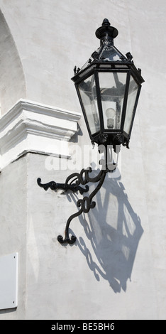 Antigua lámpara de hierro forjado en una gris pared enlucidas, en una puerta. Foto de stock