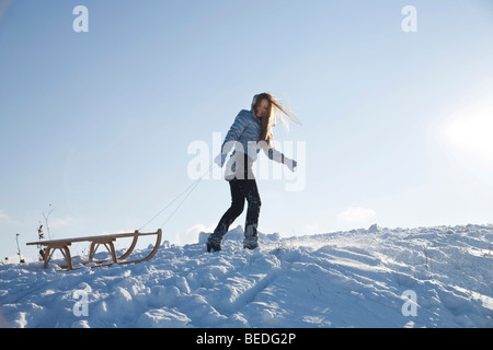 Mujer joven tirando de un trineo en la nieve. Foto de stock