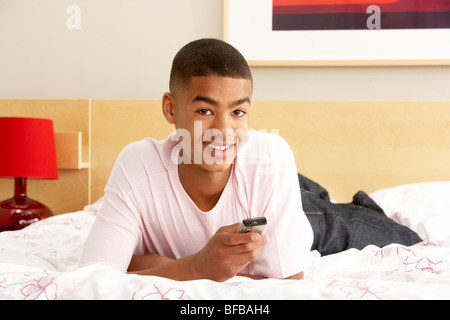 Adolescente en dormitorio con teléfono móvil