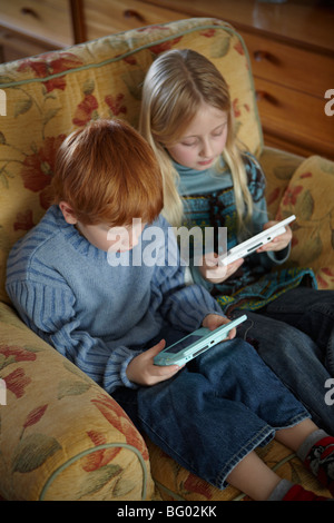 Niño y niña jugando Nintendo DS Foto de stock