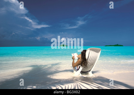 Mujer leyendo un libro en la playa, Maldivas, Océano Índico, Asia