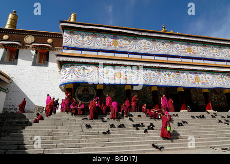 Los monjes tibetanos en el salpicadero de la orden Gelukpa sentada en las escaleras de la sala de la Asamblea, Dukhang tibetano, monasterio de Labrang, Xia Foto de stock