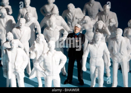 Figuras de plástico en miniatura, multitud de personas. Una figura pintada, rodeada por pintar figuras blancas. Foto de stock