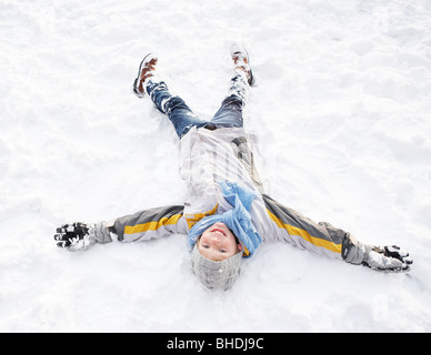 Niño acostado en el suelo haciendo Ángel de nieve