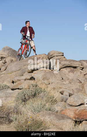 El hombre permanece con mountain bike en afloramiento rocoso