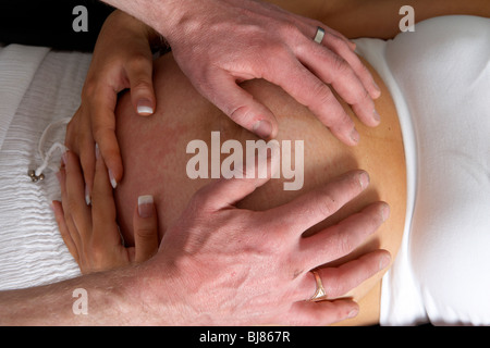 Embarazada de 8 meses a 30 años de edad con 37 años pareja masculina manos sobre la protuberancia Foto de stock