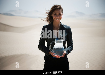 Estados Unidos, Utah, pequeño Sáhara, joven empresaria de pie en desierto celebración jarra de agua Foto de stock
