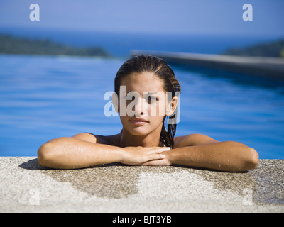 Mujer descansa sobre cornisa de piscina Foto de stock