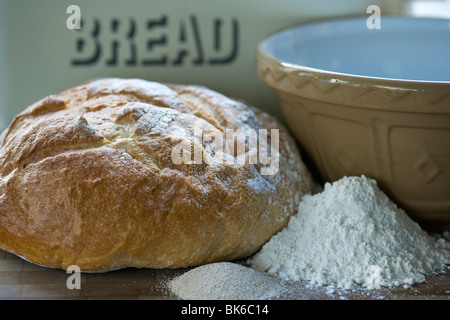 Una hogaza de pan blanco recién horneado con ingredientes y tazón