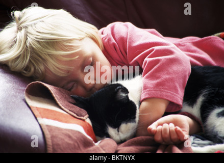 Niño durmiendo con gato mascota en el sofá