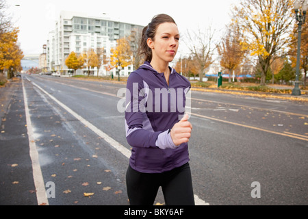 Una prueba de atletismo femenino en una chaqueta de color púrpura que corre a lo largo de una calle desierta en Portland, Oregon.