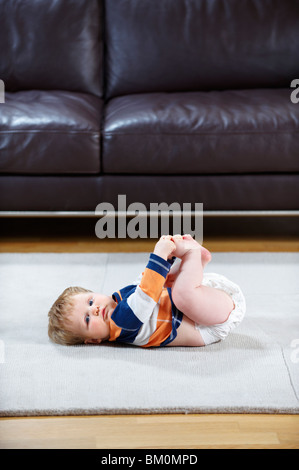 Bebé de 8 meses en pañal acostado sobre una alfombra Foto de stock