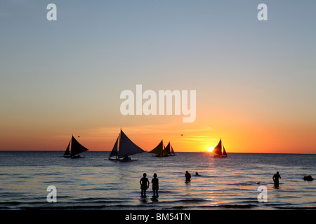 Barcos de vela de telas de la línea de la orilla al atardecer en la Playa Blanca, Boracay, el destino turístico más famoso en Filipinas.