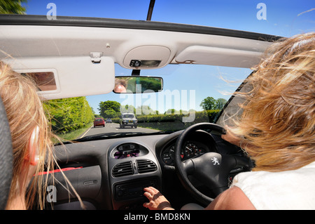 Open top coche con conductor y pasajero femenino en carretera abierta
