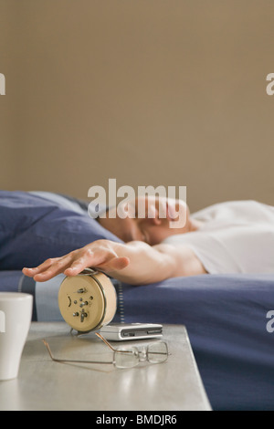 Hombre durmiendo apagar el despertador Foto de stock