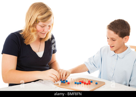 Hermano y hermana jugando un juego de damas chinas (este es un juego genérico, no un nombre de marca). Fondo blanco. Foto de stock