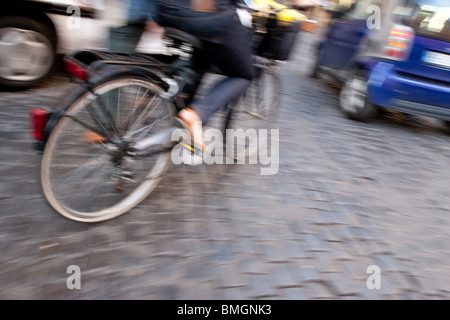 Mujer pedaleando una bicicleta en la calle de la ciudad de Roma Italia Mujer pedaleando una bicicleta en la calle de la ciudad de Roma Italia