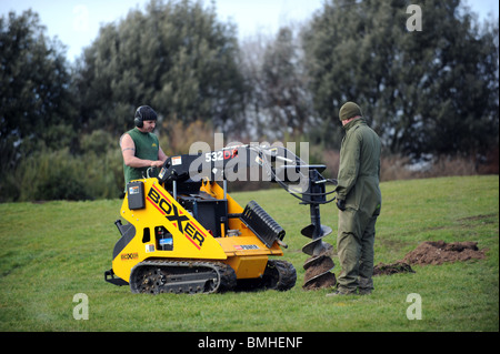 Un consejo trabajador usa un poder boxer excavadora para excavar agujeros para los árboles para las ciudades proyecto en Brighton Foto de stock