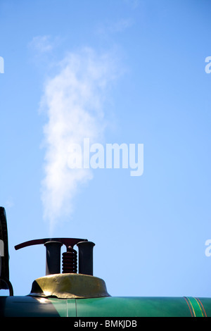 El vapor de una válvula de alivio de presión sobre una locomotora de vapor de tren contra un cielo azul Foto de stock