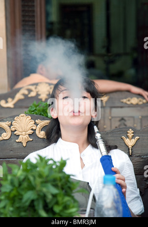 Mujer joven fumando un narguile shisha tubo (tubo) en una cafetería en El Cairo, Egipto Foto de stock