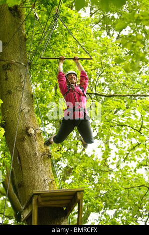 Adolescente sobre cuerdas en los árboles como parte de un curso organizado por la Urdd Outward Bound Adventure Centre, Glanllyn UK Foto de stock