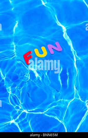 La palabra diversión hechas de espuma letras flotando sobre la superficie del agua de una piscina Foto de stock