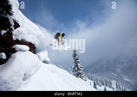 Un snowboarder salta desde un acantilado en polvo en Colorado. Foto de stock