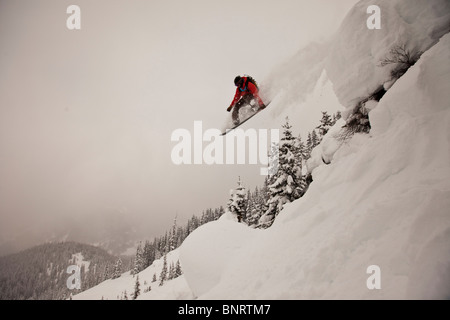 Un snowboarder salta desde un acantilado en polvo en Colorado. Foto de stock