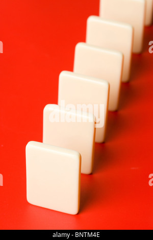 Domino con fondo rojo, el concepto de causa o de trabajo en equipo Foto de stock