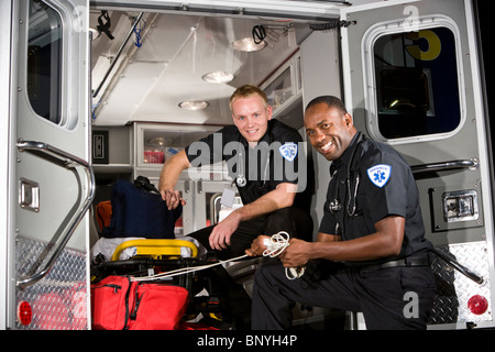 Los paramédicos multirracial preparar equipos médicos en la ambulancia Foto de stock