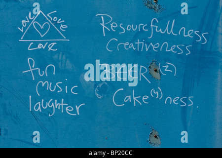 Divertido graffiti en una pared azul ensalzando el amor divertida música y risas. Y cerveza. Todo lo que necesitamos para un mundo mejor.