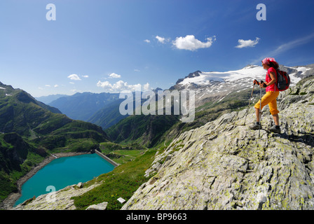 Caminante en busca hembra sobre depósito Lago di Robiei Basodino, en el fondo, los glaciares de los Alpes de Ticino, Tesino, Suiza Foto de stock