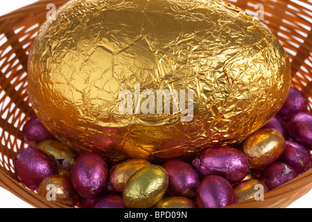 Lámina de oro grandes y pequeñas de chocolate envuelto en una canasta de huevos de Pascua Foto de stock