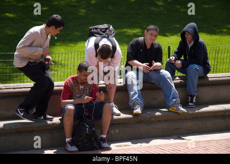 Un grupo de muchachos adolescentes rondando juntos escuchando sus ipods Foto de stock