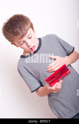 Un modelo liberado imagen de un muchacho de 10 años de edad jugando con una consola de juegos portátil Nintendo DS en el studio Foto de stock